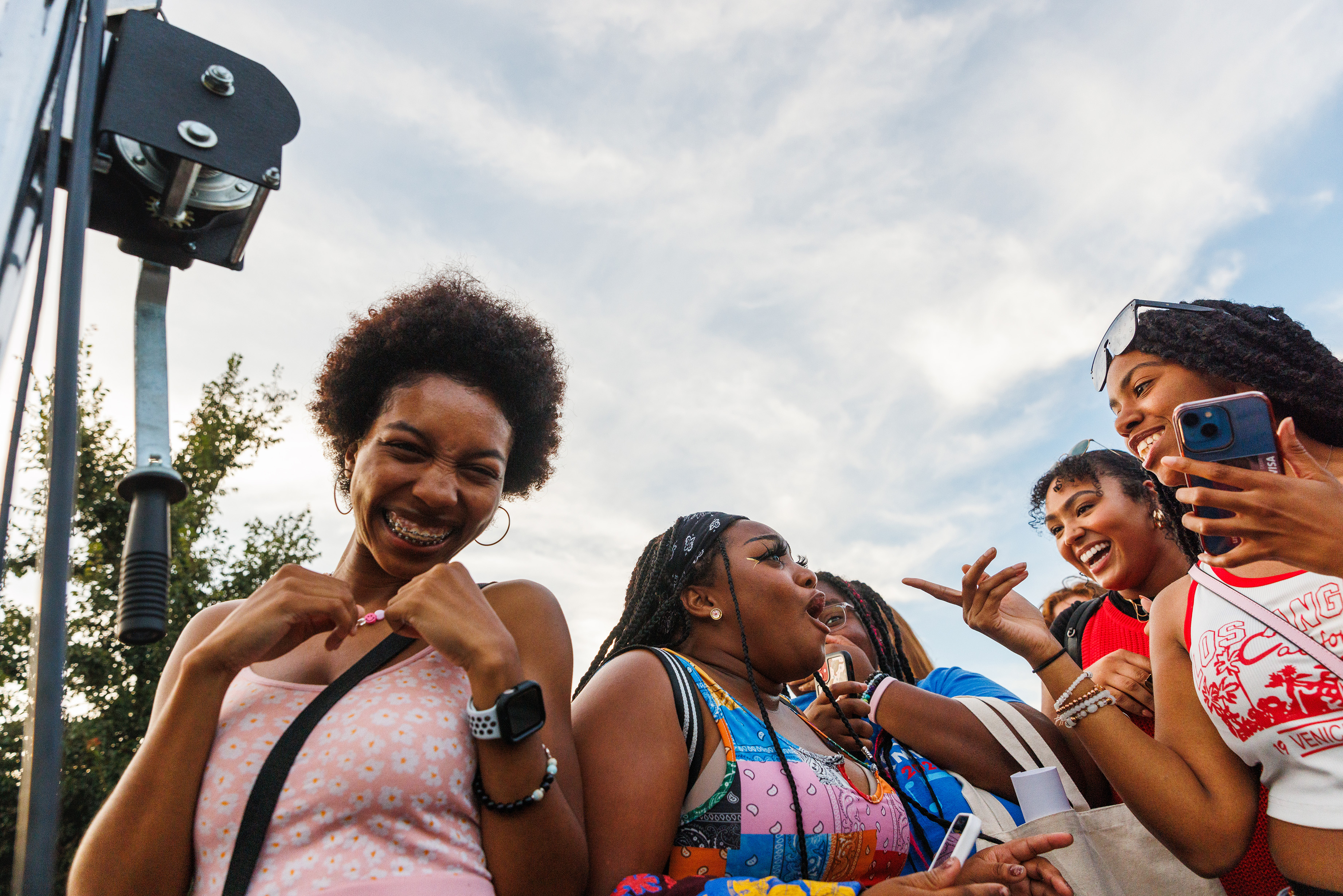 A student smiles at the camera, while surrounded by friends.